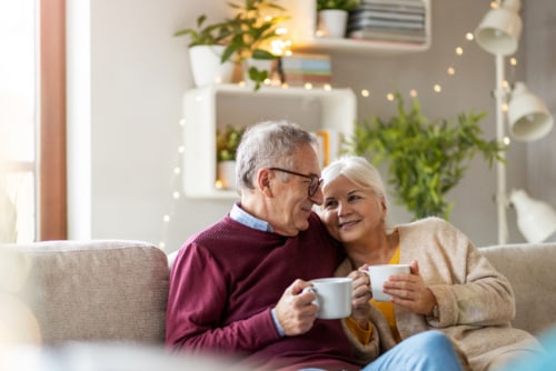 wertvollER: Glückliches Ehepaar auf dem Sofa Glückliches Ehepaar sitzt mit Teetassen auf dem Sofa