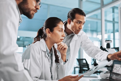 Onkologin und zwei Onkologen schauen sich Laborergebnisse auf dem Computer an