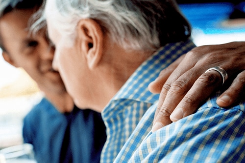 Sohn legt tröstend und positiv zugewandt seinen Arm um seinen Vater